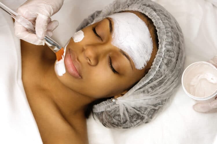 Application of a cosmetology mask African american woman getting a chemical peel scaled e1657815146107