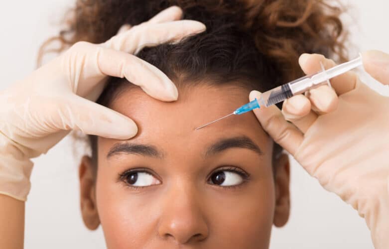 African-american woman getting injectables injection in forehead African american woman getting injectables in forehead scaled e1657806648669