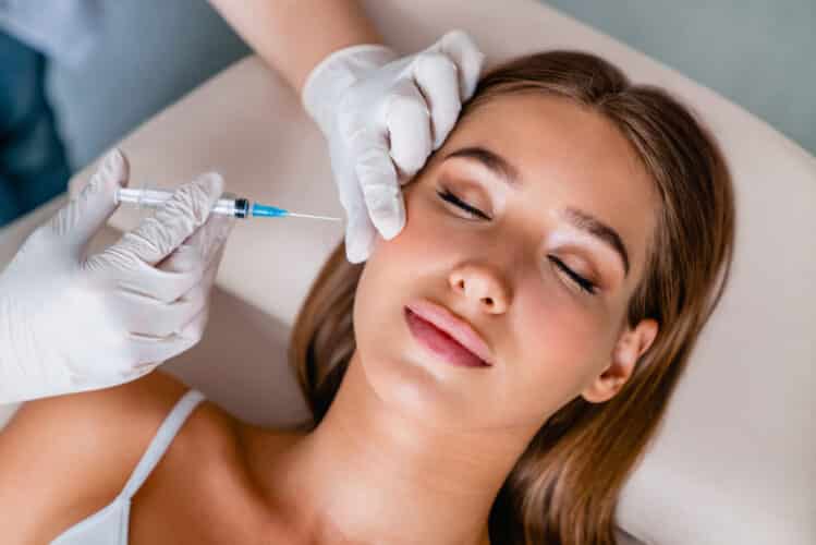 Young woman gets beauty facial injections in salon Injectables