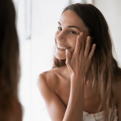 Woman doing her skincare routine at a mirror, newport news dermatologist