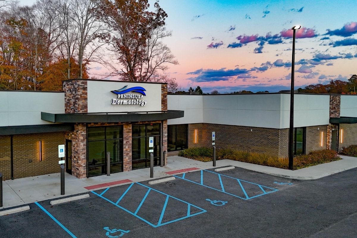 Aerial view of a modern medical office building surrounded by trees and open landscape at sunset.