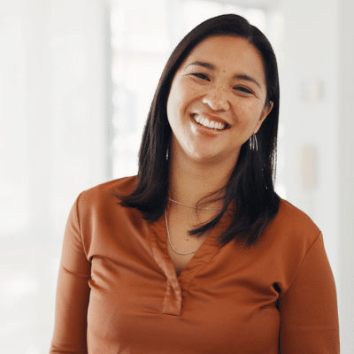 The truth about natural vs synthetic skincare 2 Woman smiling in brown top, neutral background, representing natural vs synthetic skincare